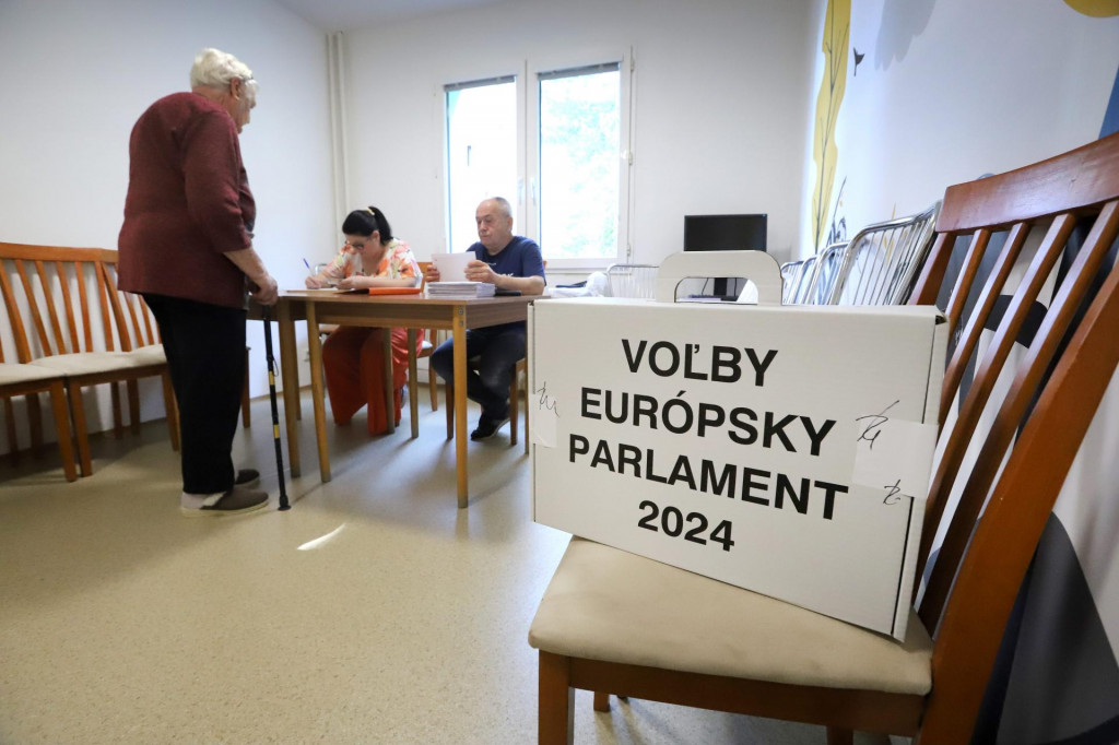 Dôchodkyňa si preberá hlasovacie lístky od členov volebnej komisie vo volebnej miestnosti v zariadení pre seniorov Jeseň počas volieb do Európskeho parlamentu v Banskej Bystrici. FOTO: TASR/Ján Krošlák