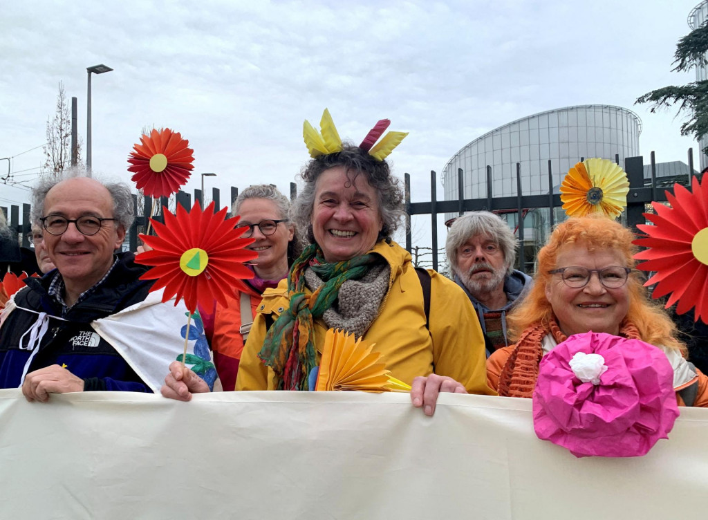 Podporovatelia združenia Senior Women for Climate Protection držia pred Európskym súdom pre ľudské práva v Štrasburgu papierové kvety a transparent. FOTO: Reuters