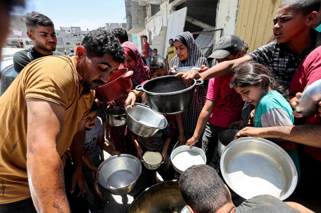 Palestínčania sa zhromažďujú, aby dostali jedlo varené v charitatívnej kuchyni v blízkosti domov zničených pri izraelskej vojenskej ofenzíve. FOTO: Reuters