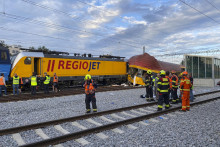 Hasiči stoja vedľa dvoch vlakov po zrážke v Pardubiciach. FOTO: TASR/AP