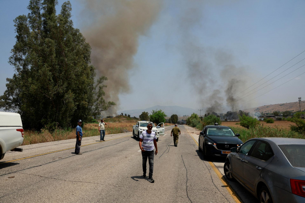 Izraelčania sa zhromažďujú na ceste v blízkosti požiaru po útokoch z Libanonu. FOTO: Reuters