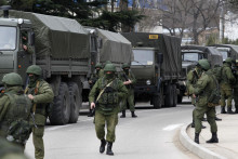 Ozbrojení vojaci čakajú pri vozidlách ruskej armády. FOTO: Reuters