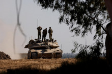 Izraelskí vojaci stoja na vrchu tanku neďaleko izraelsko-gazskej hranice. FOTO: Reuters