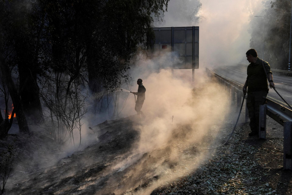 Izraelskí vojaci hasia plamene po cezhraničných akciách medzi Hizballáhom a izraelskými silami. FOTO: Reuters