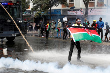 Demonštrant drží kenskú vlajku, zatiaľ čo polícia používa vodné delá a slzný plyn na rozohnanie davu. FOTO: Reuters