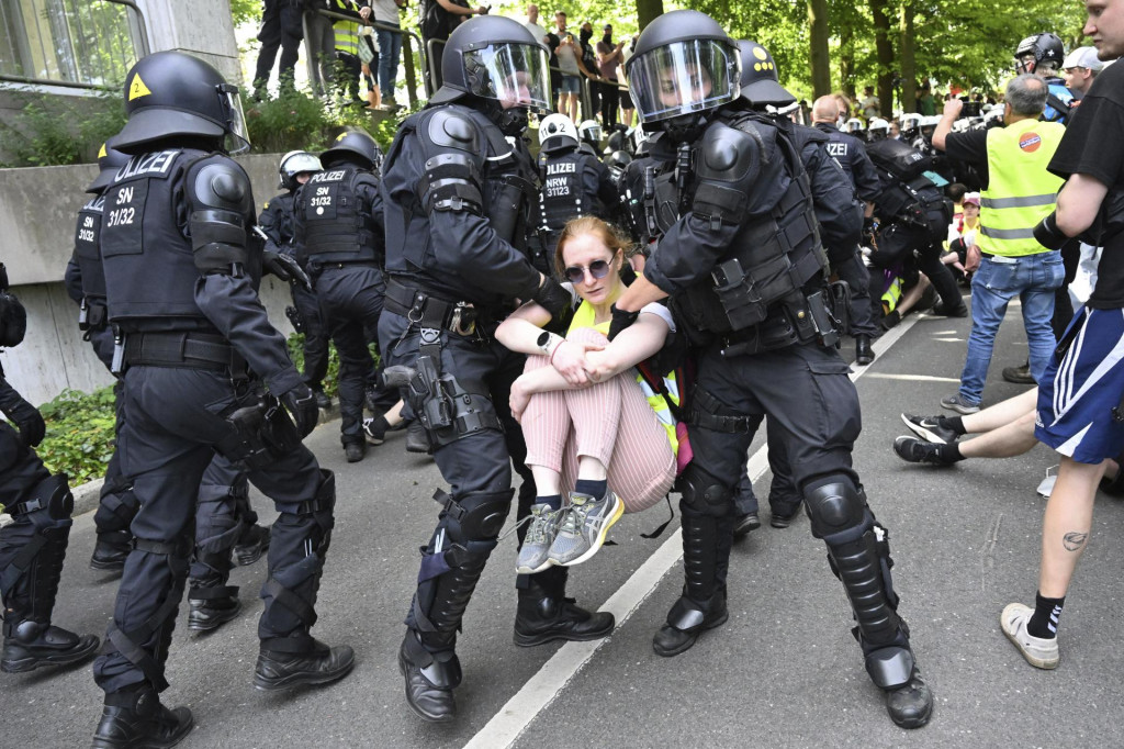 Policajti odnášajú demonštrantku, ktorá spolu s ďalšími blokovala cestu v nemeckom Essene. FOTO: TASR/AP