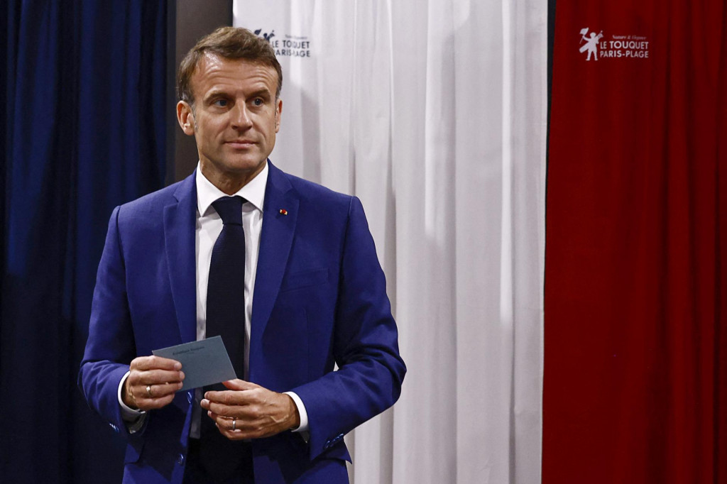 Francúzsky prezident Emmanuel Macron drží v ruke obálku s hlasovacím lístkom vo volebnej miestnosti v obci Le Touquet-Paris-Plage počas 1. kola predčasných parlamentných volieb vo Francúzsku. FOTO: TASR/AP