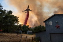Hasiči zhadzujú retardér z lietadla vedľa domu, keď bojujú s lesným požiarom v kaňone v Oroville v Kalifornii. FOTO: Reuters