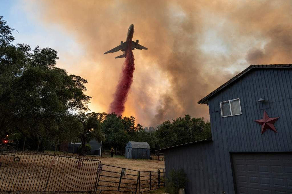 Hasiči zhadzujú retardér z lietadla vedľa domu, keď bojujú s lesným požiarom v kaňone v Oroville v Kalifornii. FOTO: Reuters