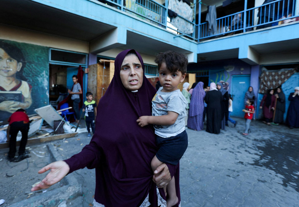 Palestínska žena nesúca dieťa reaguje po izraelskom nálete na školu OSN ukrývajúcu vysídlené osoby v tábore Nusajrát. FOTO: Reuters