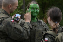 Dobrovoľníci učia sa aplikovať na tvár kamufláž počas vojenského výcviku v poľskom meste Nowogród. FOTO: TASR/AP
