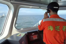 Člen posádky taiwanskej pobrežnej stráže hovorí cez megafón k posádke lode čínskej pobrežnej stráže neďaleko pobrežia pri taiwanskom okrese Kinmen. FOTO: TASR/AP