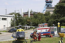 Záchranári prevážajú zraneného baníka do helikoptéry pred uhoľnou baňou Rydultowy v južnom Poľsku. FOTO: TASR/AP