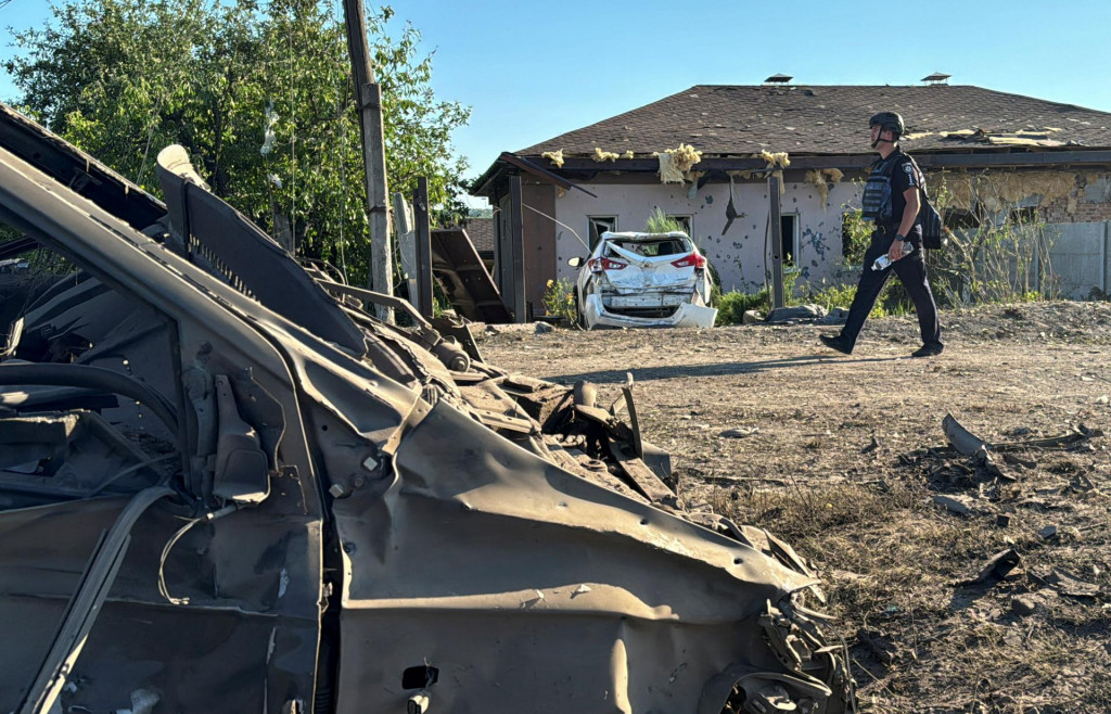 Policajt prechádza v blízkosti poškodených áut na mieste ruského raketového útoku. FOTO: Reuters