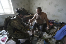 Policajt poskytuje lekársku pomoc miestnemu mužovi, ktorého zranil ruský nálet. FOTO: TASR/AP