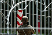 Vojak stojí na stráži pri plote na bielorusko-poľskej hranici v lese pri Bialowieze v Poľsku. FOTO: Reuters