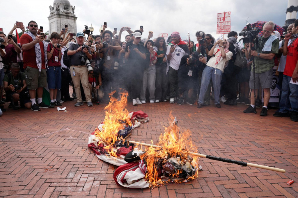 Demonštranti okolo horiacej americkej vlajky. FOTO: Reuters