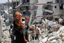 Palestínska žena drží svoju dcéru, keď prechádza popri troskách domov zničených počas izraelskej vojenskej ofenzívy v Chán Júnis v južnom Pásme gazy. FOTO: Reuters