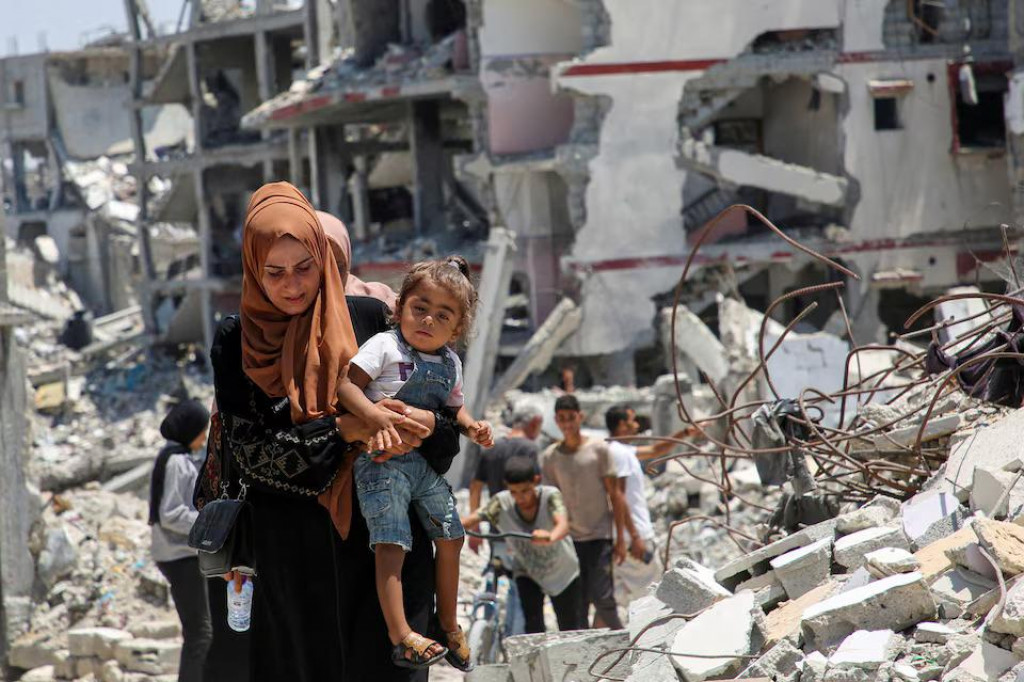 Palestínska žena drží svoju dcéru, keď prechádza popri troskách domov zničených počas izraelskej vojenskej ofenzívy uprostred konfliktu medzi Izraelom a Hamasom v Khan Younis v južnom pásme Gazy. FOTO: Reuters