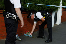 Policajt umiestňuje kvety darované obyvateľmi v blízkosti miesta útoku nožom v anglickom Southporte. FOTO: Reuters