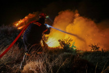 Hasič sa pokúša uhasiť požiar, ktorý horí pri obci Petries na gréckom ostrove Eubója. FOTO: Reuters