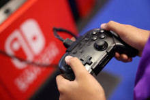 Účastník používa hernú konzolu Nintendo Switch pri hraní videohry. FOTO: Reuters