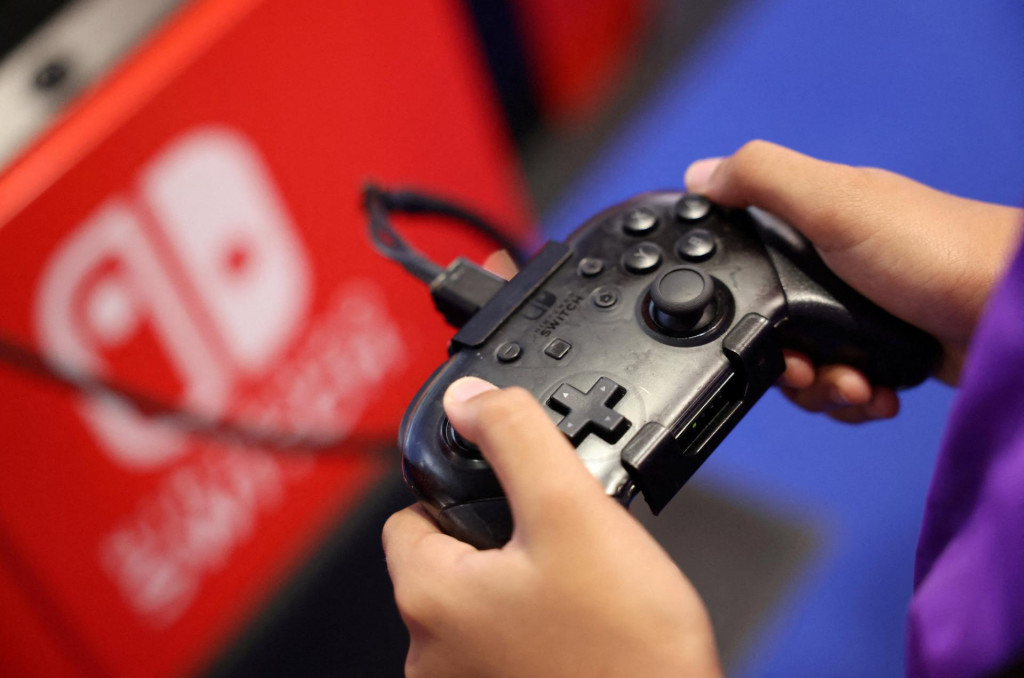 Účastník používa hernú konzolu Nintendo Switch pri hraní videohry. FOTO: Reuters