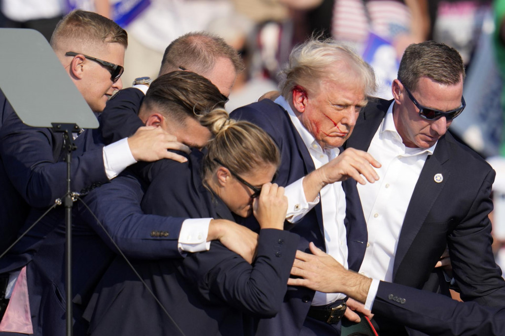 Republikánsky prezidentský kandidát Donald Trump (druhý sprava) odchádza za pomoci ochrankárov z predvolebného mítingu v meste Butler v americkom štáte Pensylvánia. FOTO: TASR/AP