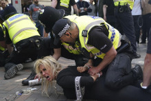 Policajti zadržujú ženu počas protestu v Nottinghame. FOTO: TASR/AP