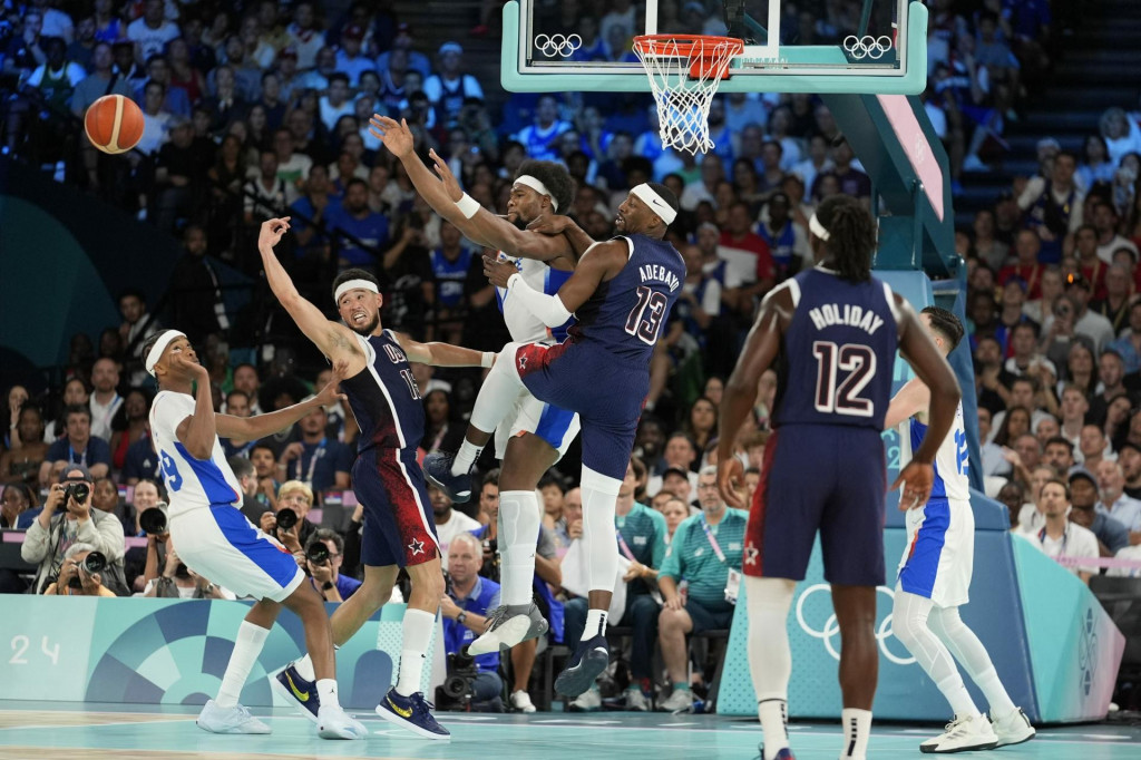 Bilal Coulibaly (99) z Francúzska, Devin Booker (15), Guerschon Yabusele (7) z Francúzska a Bam Adebayo (13) z USA bojujú o držanie lopty počas basketbalového zápasu mužov o zlatú medailu v Bercy Arene v hale. FOTO: TASR/AP