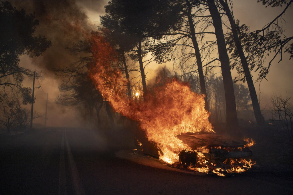 Auto horí počas lesných požiarov v gréckej dedine. FOTO: TASR/AP