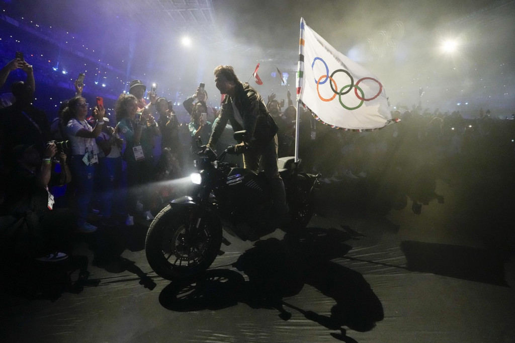 Herec Tom Cruise jazdí na motorke s olympijskou zástavou počas záverečného ceremoniálu XXXIII. letných olympijských hier na štadióne Stade de France v Paríži. FOTO: TASR/AP