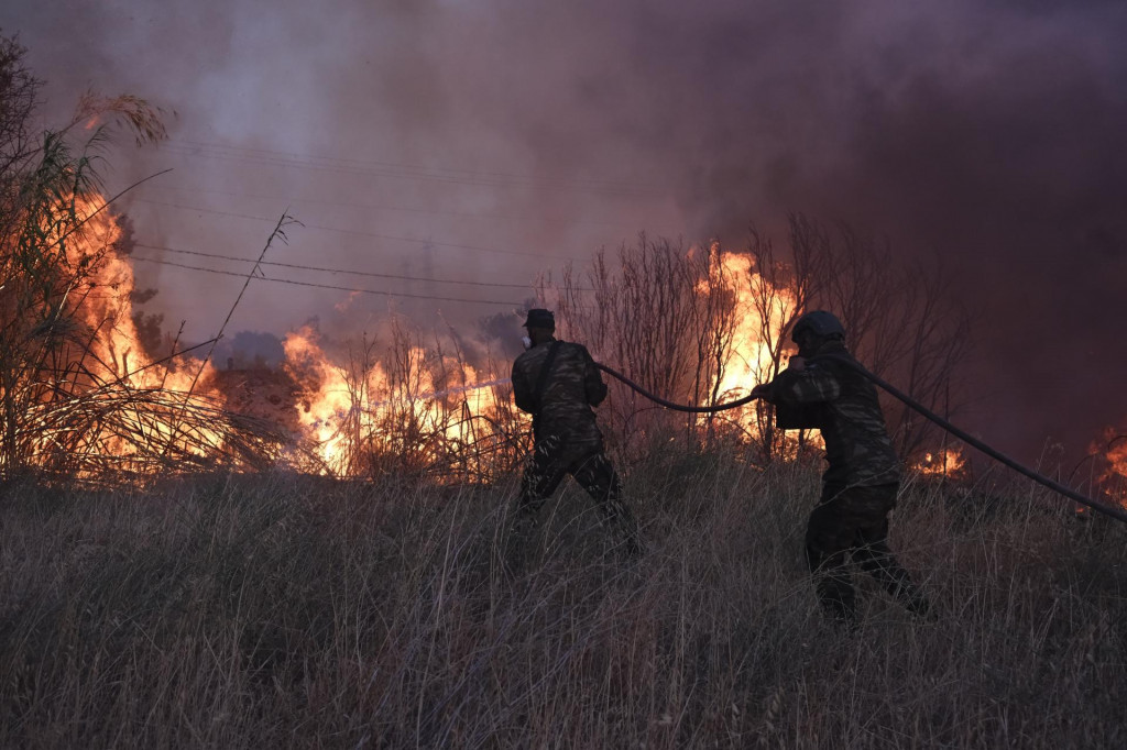 Dobrovoľníci sa snažia uhasiť požiar v Aténach. FOTO: TASR/AP