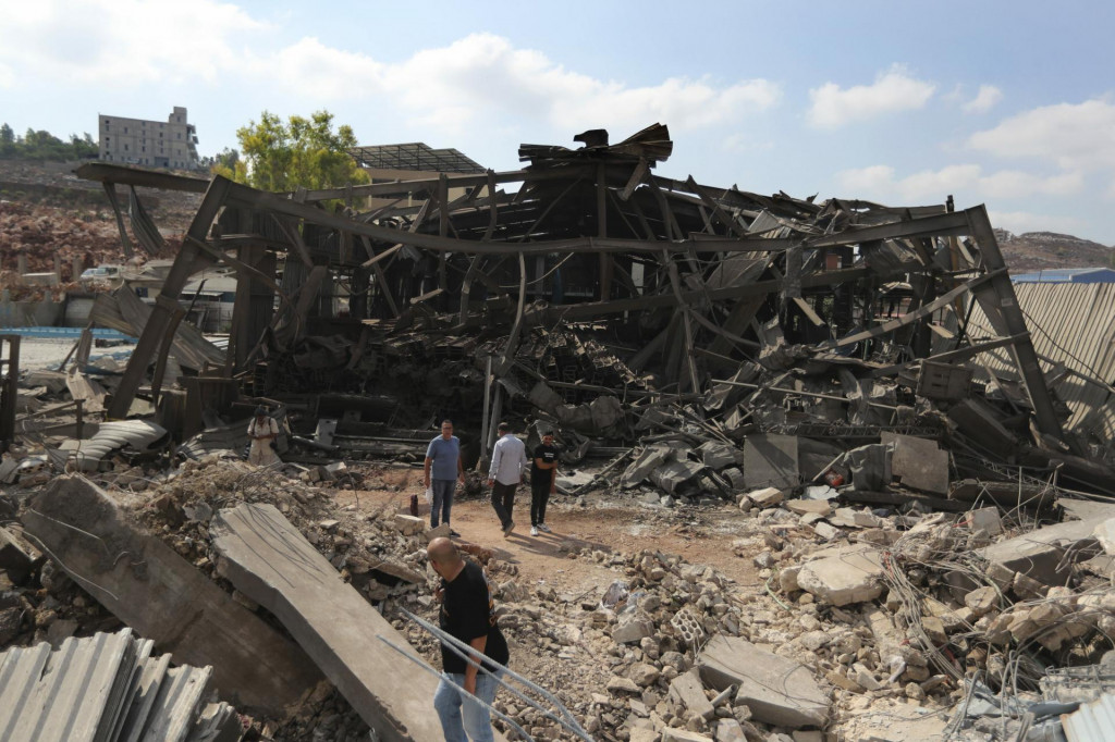 Ľudia kráčajú v priemyselnej oblasti zničenej izraelským náletom vo Wadi al-Kfour, provincia Nabatíja. FOTO: TASR/AP