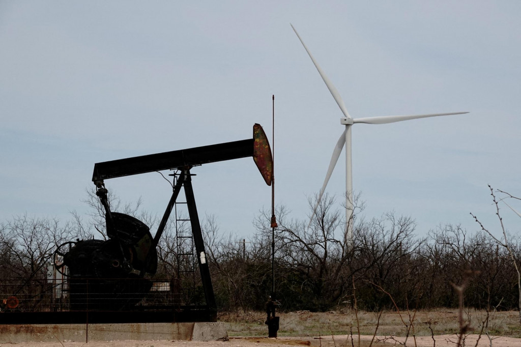 FILE PHOTO: A pump jack drills oil crude from the Yates Oilfield in West Texas‘s Permian Basin, as a 1.5MW GE wind turbine from the Desert Sky Wind Farm is seen in the distance, near Iraan, Texas, U.S., March 17, 2023. REUTERS/Bing Guan/File Photo FOTO: Bing Guan