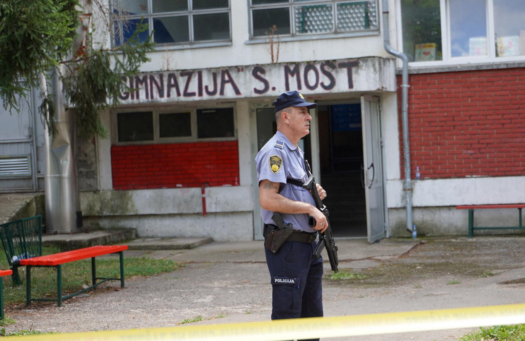 Policajt stráži pred budovou strednej školy, kde muž spustil paľbu a zabil troch zamestnancov v meste Sanski Most na severozápade Bosny a Hercegoviny. FOTO: Reuters