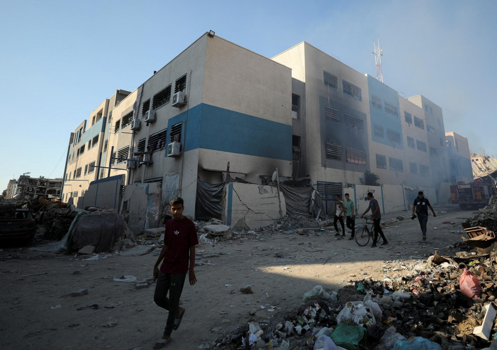 Palestínčania kráčajú v blízkosti školy, ktorá ukrýva vysídlených ľudí po tom, čo ju zasiahol izraelský útok. FOTO: Reuters