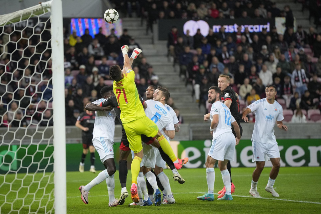 Brankár Slovana Dominik Takáč vyráža loptu, dole pod ním jeho spoluhráč a rakúsky obranca Kevin Wimmer v úvodnom zápase play off Ligy majstrov vo futbale FC Midtjylland - ŠK Slovan Bratislava v dánskom Herningu. FOTO: TASR/AP