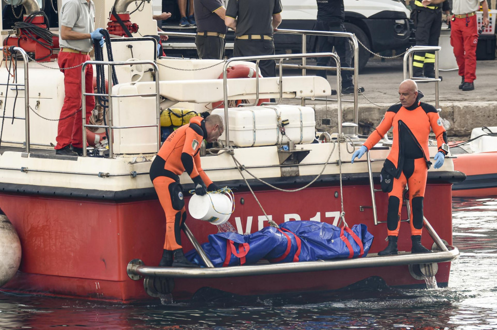 Talianski potápači vynášajú telo jednej z obetí potopenej plachetnice Bayesan v prístave v meste Porticello. FOTO: TASR/AP
