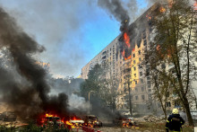 Hasič sa pozerá na bytový dom a autá, ktoré horia po ruskom nálete uprostred ruského útoku na Ukrajinu v Charkove. FOTO: Reuters