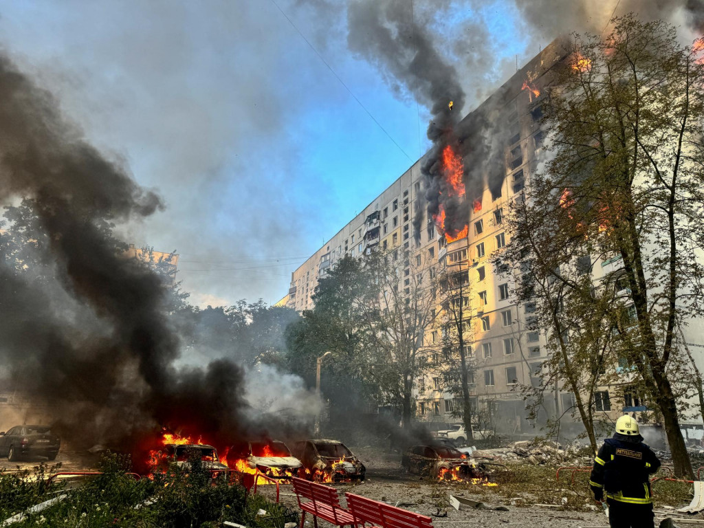 Hasič sa pozerá na bytový dom a autá, ktoré horia po ruskom nálete uprostred ruského útoku na Ukrajinu v Charkove. FOTO: Reuters