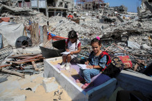 Palestínski študenti sedia na troskách po tom, čo navštevovali hodinu v stane postavenom na ruinách domu učiteľa, keď vojna narušila nový školský rok. FOTO: Reuters