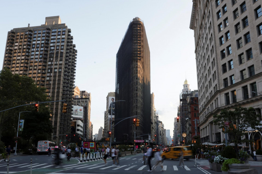 Ľudia prechádzajú cez ulicu neďaleko rozostavanej budovy Flatiron v New Yorku. FOTO: Reuters