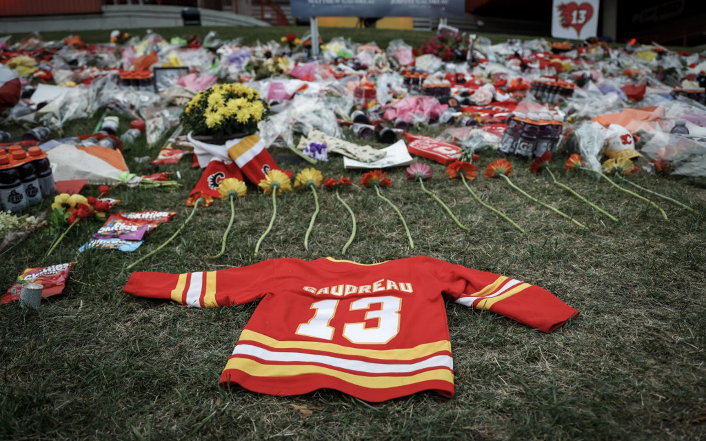 Kvety a spomienkové predmety pre bývalého hráča Calgary Flames Johnnyho Gaudreaua a jeho brata Matthewa sú položené na tráve pred halou Saddledome v Calgary. FOTO: TASR/AP