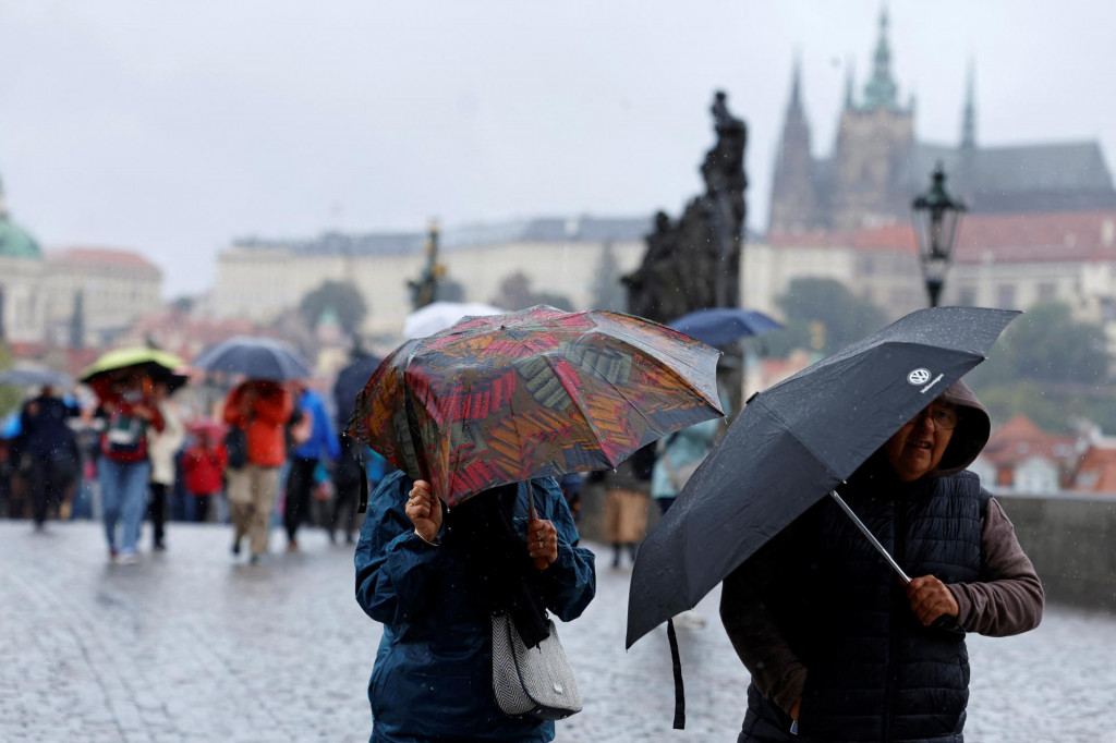 Ľudia sa prechádzajú cez stredoveký Karlov most počas búrky v Prahe. FOTO: Reuters