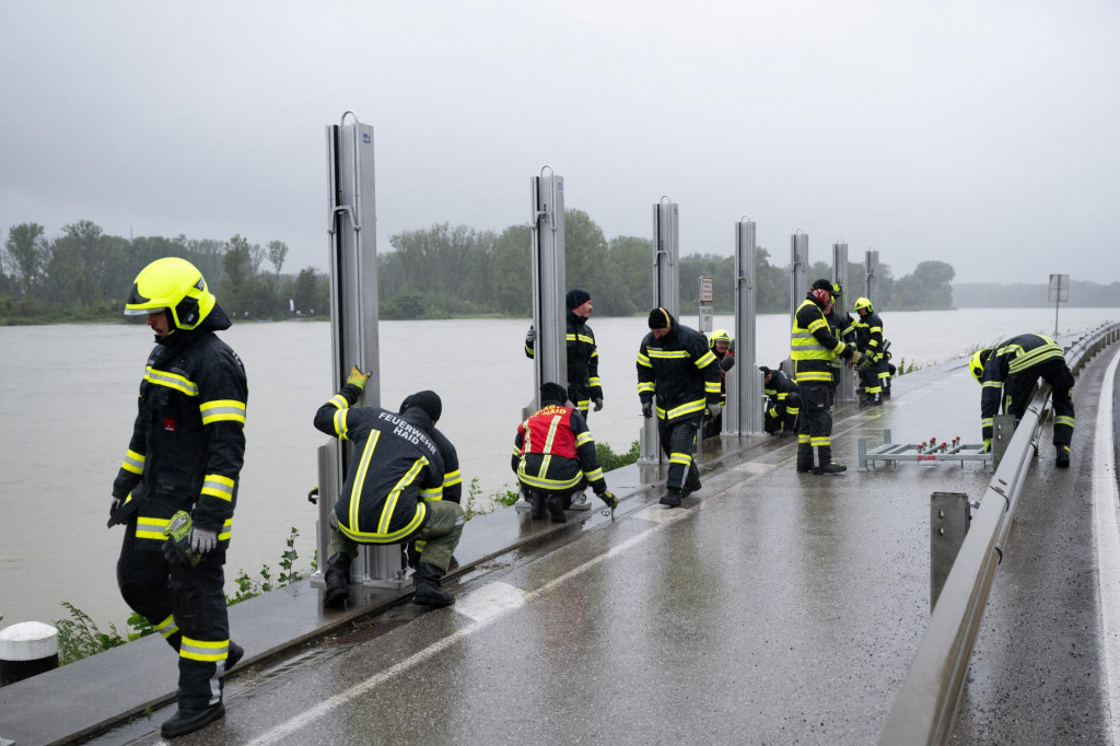 Hasiči montujú vodnú bariéru pri rieke Dunaj, aby zabránili rozliatiu povodňovej vody do ulíc v rakúskom Mauthausene. FOTO: REUTERS