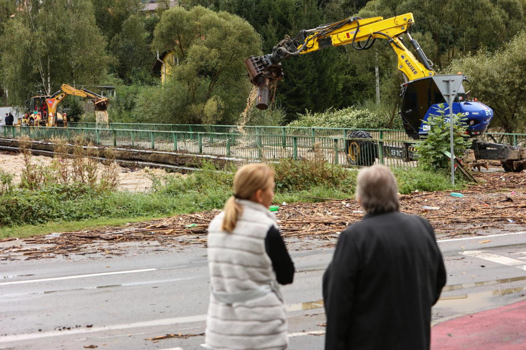 Ženy sledujú ťažkú techniku ako spriechodňuje zaplavený most počas tretieho stupňa povodňovej aktivity na rieke Kysuca v mestskej časti Čadca-Horelica. FOTO: TASR/Daniel Stehlík