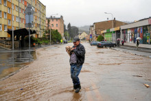 Muž drží psa na zaplavenej ceste. FOTO: Reuters.