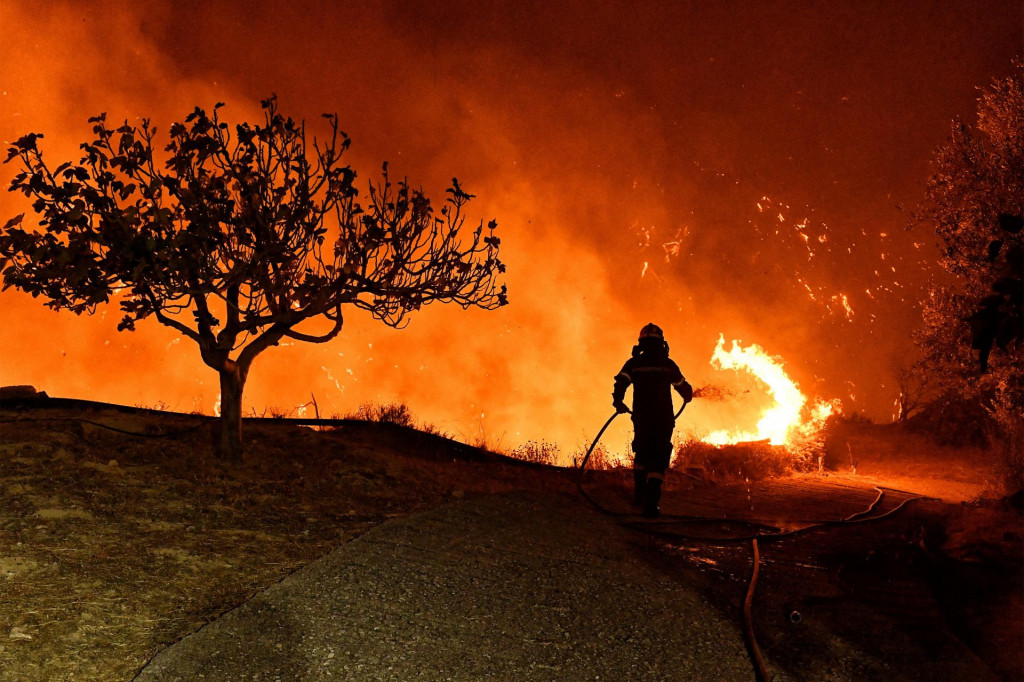 Hasič sa pokúša uhasiť požiar, ktorý horí pri dedine Kallithea neďaleko Korintu v Grécku. FOTO: Reuters