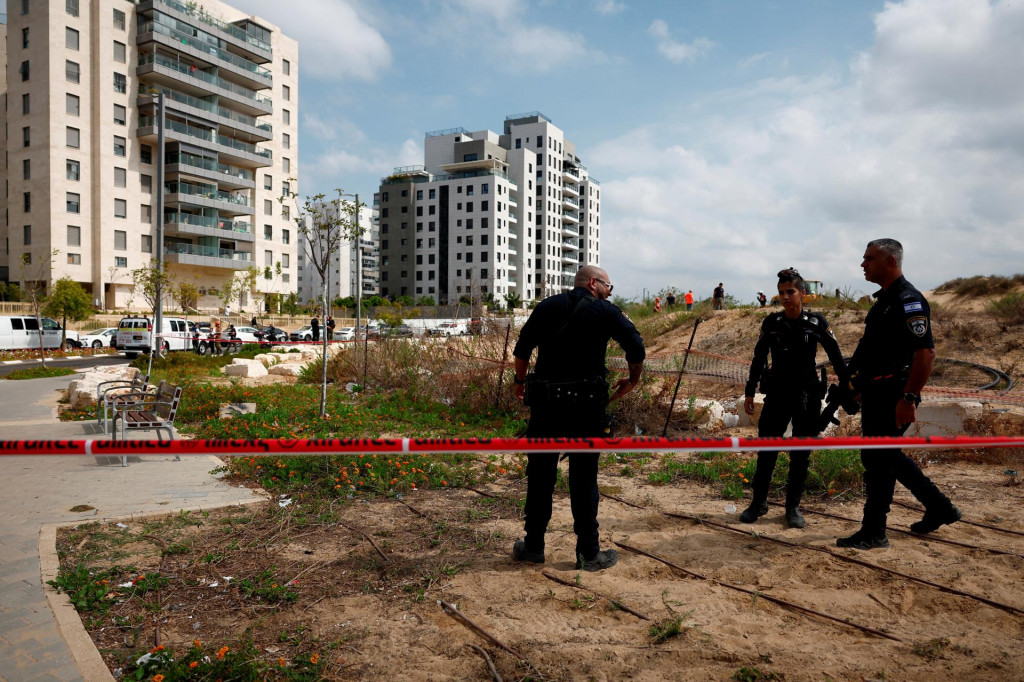 Izraelskí policajti pracujú na mieste, kde dopadol projektil v Cholone. FOTO: Reuters